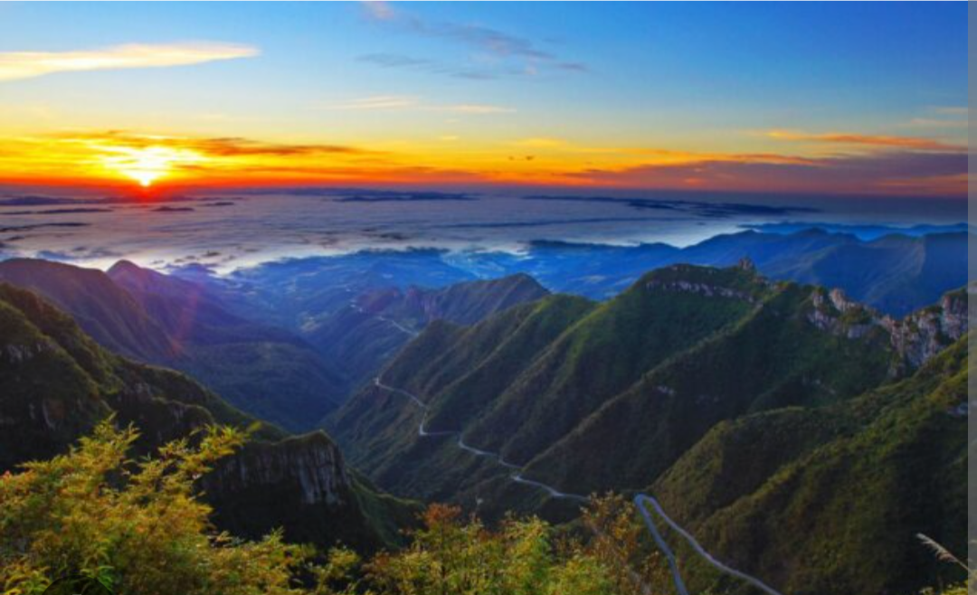 Vista panorâmica da Serra do Rio do Rastro ao amanhecer com estrada sinuosa entre montanhas
